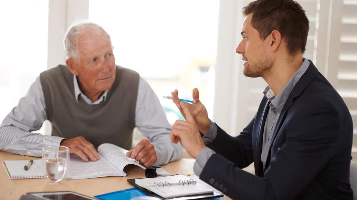 “Friends and relatives of any senior entering into a real estate deal should watch for red flags — as should the agents, lenders, title companies and other professionals involved in the transaction,” writes Lew Sichelman. Above: 
A young businessman explaining information to an elderly man.