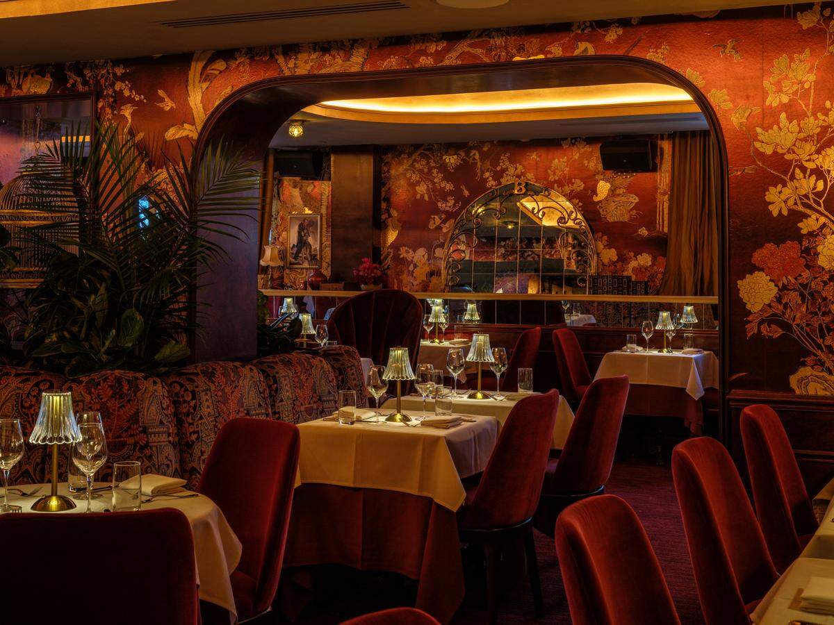 El restaurante del piso superior es elegante, con colores más oscuros, lujosas sillas rojas y papel tapiz oscuro.