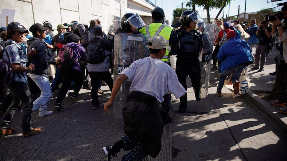 Migrants break past a line of police as they run toward the Chaparral border crossing in Tijuana, Mexico, Sunday, Nov. 25, 2018, near the San Ysidro entry point into the U.S. More than 5,000 migrants are camped in and around a sports complex in Tijuana after making their way through Mexico in recent weeks via caravan.