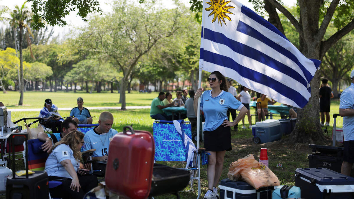 Aficionados uruguayos ondean la bandera mientras se reúnen antes del partido contra Arabia Saudí, que será este lunes, en el Tropical Park de Miami, el domingo 14 de junio de 2026.