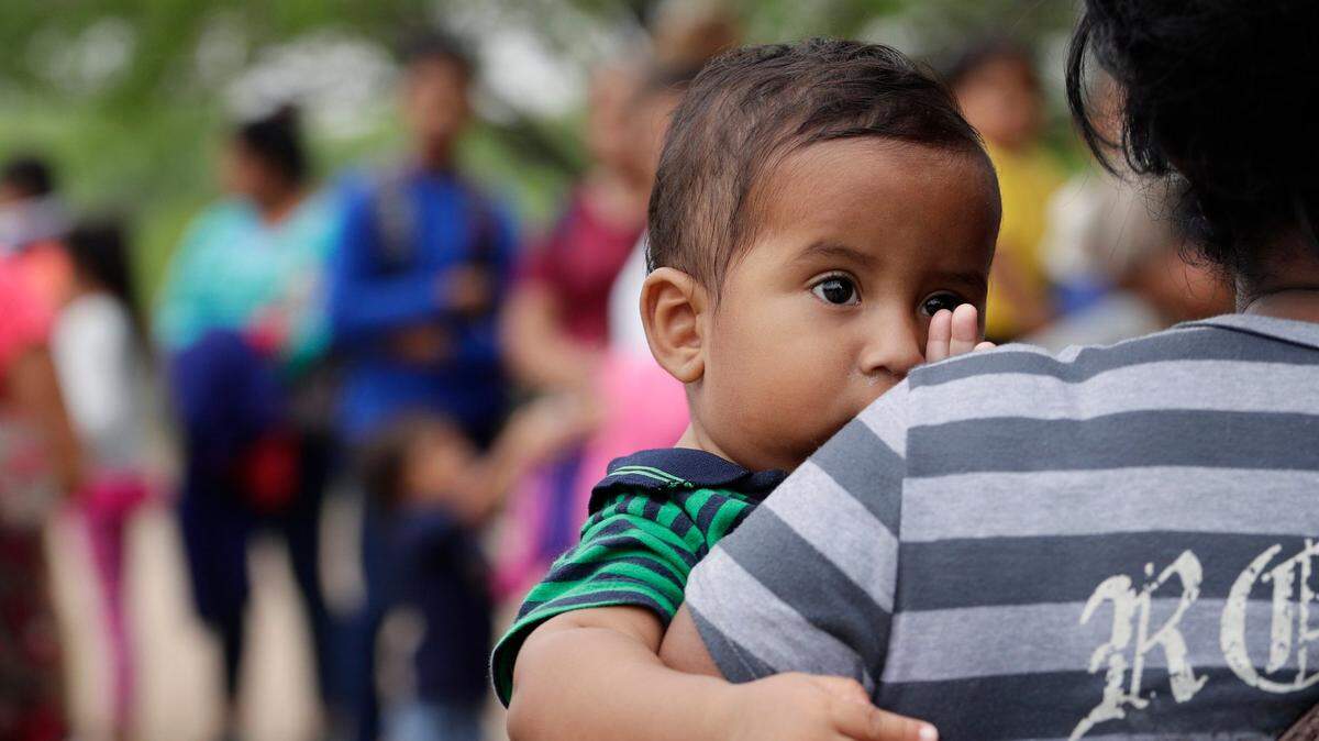 En este jueves, 14 de marzo de 2019, la foto, Lian Mejia Ruiz, de 7 meses, mira por encima del hombro de su madre, Carmen Mejía, mientras esperan que los agentes de la Patrulla Fronteriza los detengan en la frontera de EE. UU.-México cerca de McAllen, Texas. Carmen Mejía dijo que se fue de Honduras con su hijo menor debido a la pobreza.