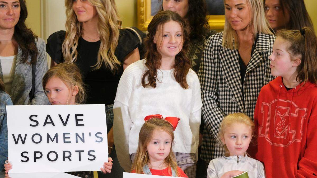 Varias personas participane en la ceremonia en donde el gobernador de Oklahoma, Kevin Stitt (no aparece en la foto), firma una ley para prohibir la participación de atletas transgénero en deportes femeninos, el miércoles 30 de marzo de 2022, en Oklahoma City.