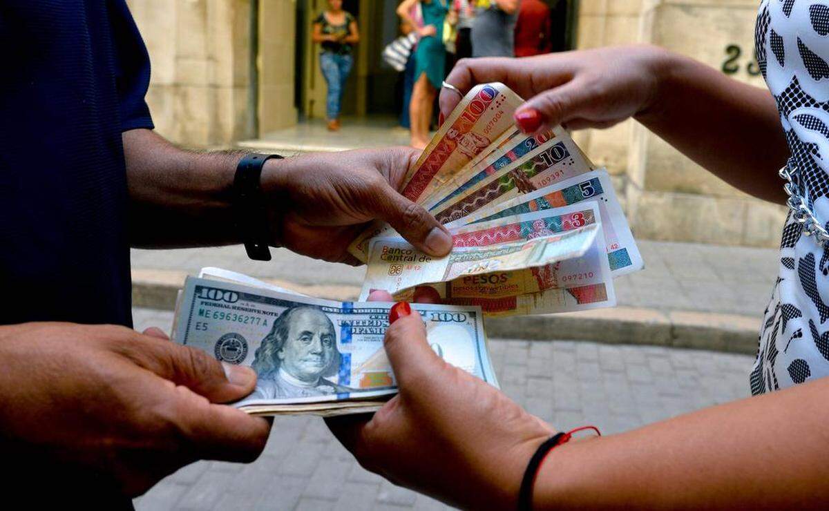 A man and woman change CUC and dollar bills on a Havana street on December 10, 2019. A month after the implementation of a deep financial reform, dollars in Cuba were more sought after than ever, and in the black market they were listed at double the official rate.