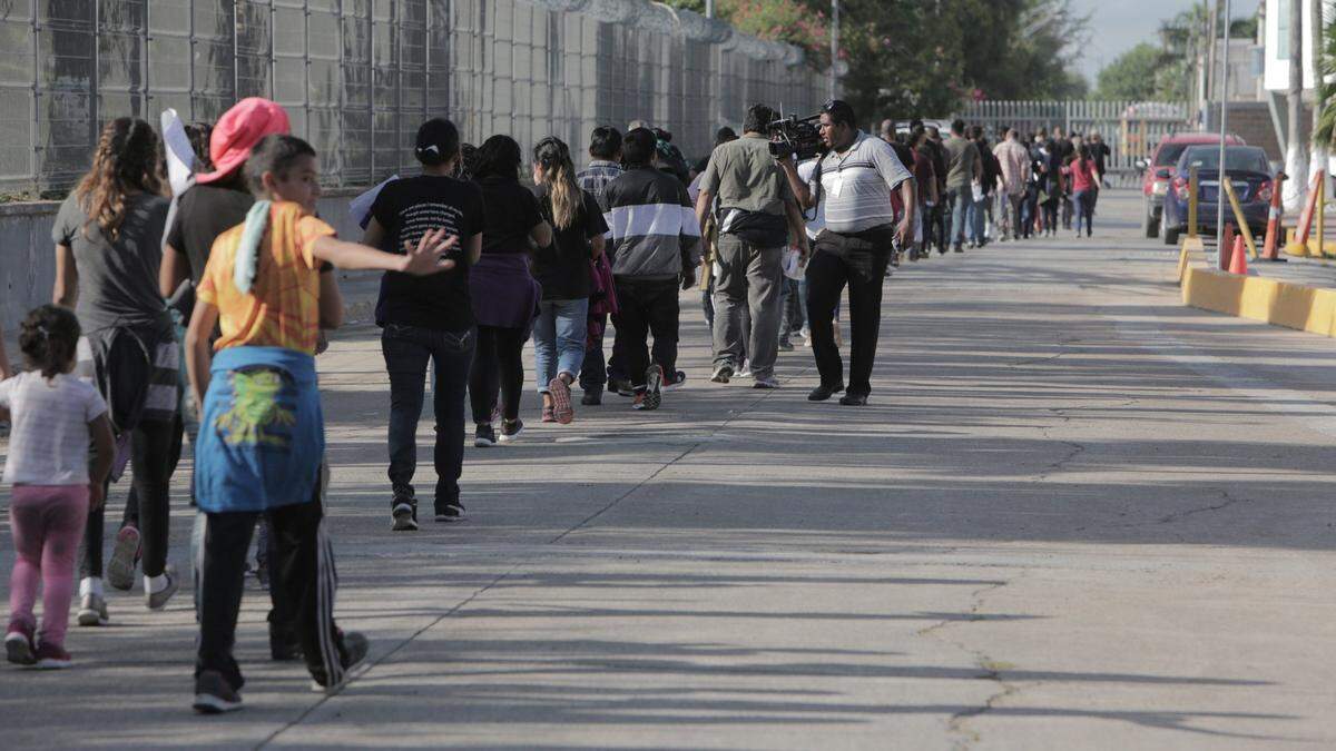 Una línea de migrantes se dirige hacia el Instituto Nacional de Migración de México, donde serán procesados una vez que sean enviados de regreso a México desde Estados Unidos.