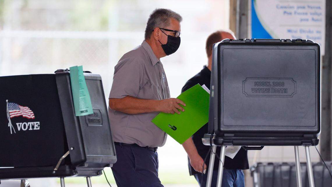 Un trabajador electoral ayuda a un elector antes de emitir su voto durante las elecciones municipales generales y especiales de Hialeah, en Miami-Dade, en la Estación de Bomberos # 5 de Hialeah, el 2 de noviembre de 2021.