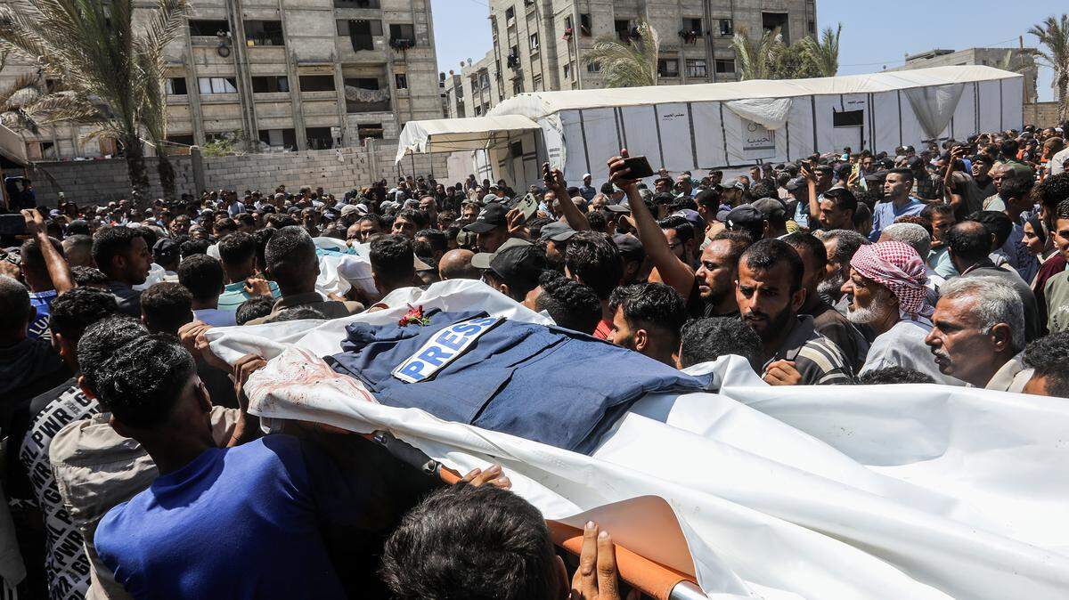 Palestinos cargan el cuerpo de un periodista que murió en un bombardeo israelí del hospital Nasser en Jan Yunis, en la Franja de Gaza, el lunes 25 de agosto de 2025.