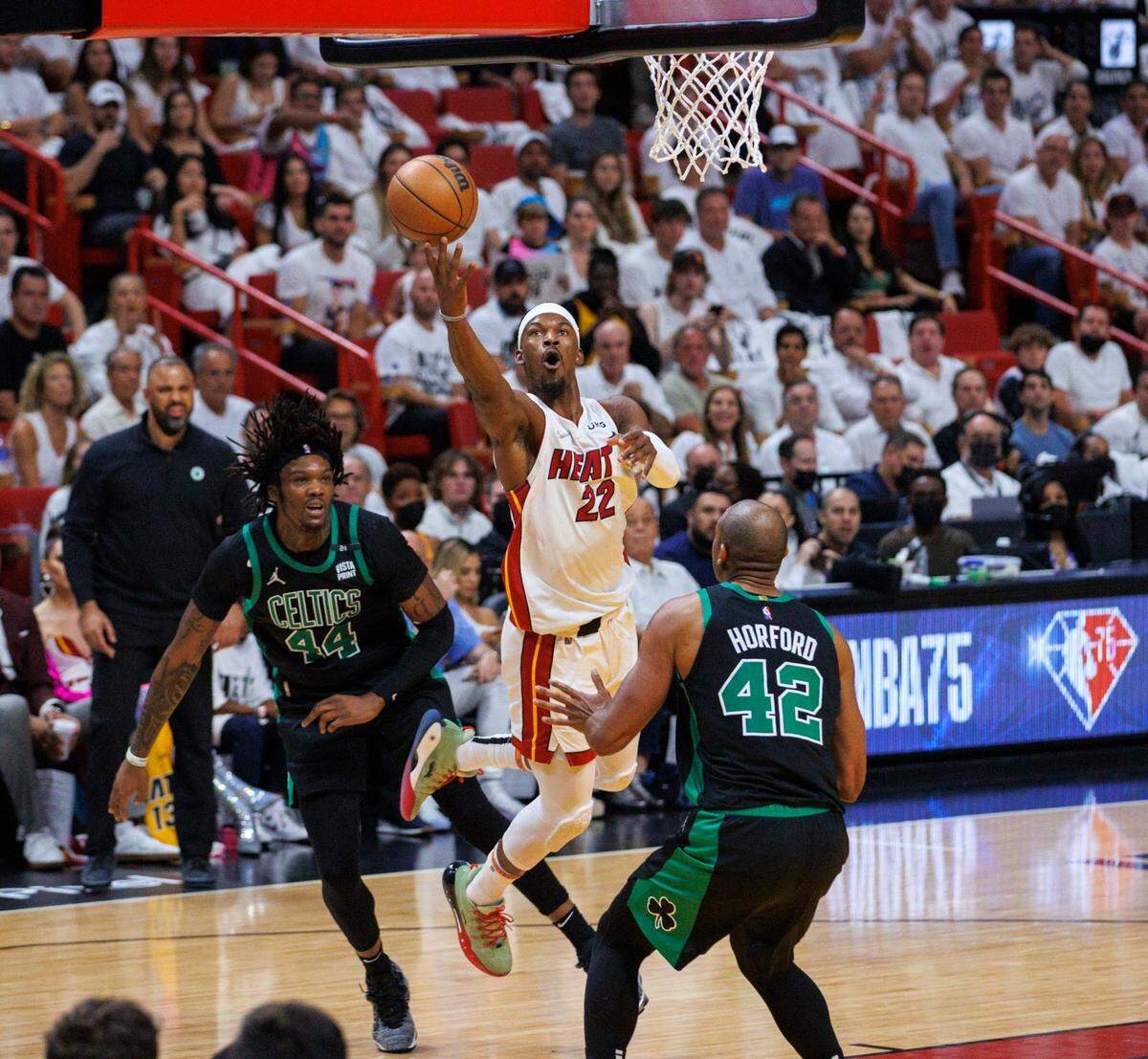 El jugador del Heat Jimmy Butler (22) entra al aro ante la marca de Robert Williams III (izq.) y Al Horford, de los Celtics de Boston, en el quinto partido de la Final de la Conferencia Este, celebrado el 25 de mayo de 2022 en Miami.