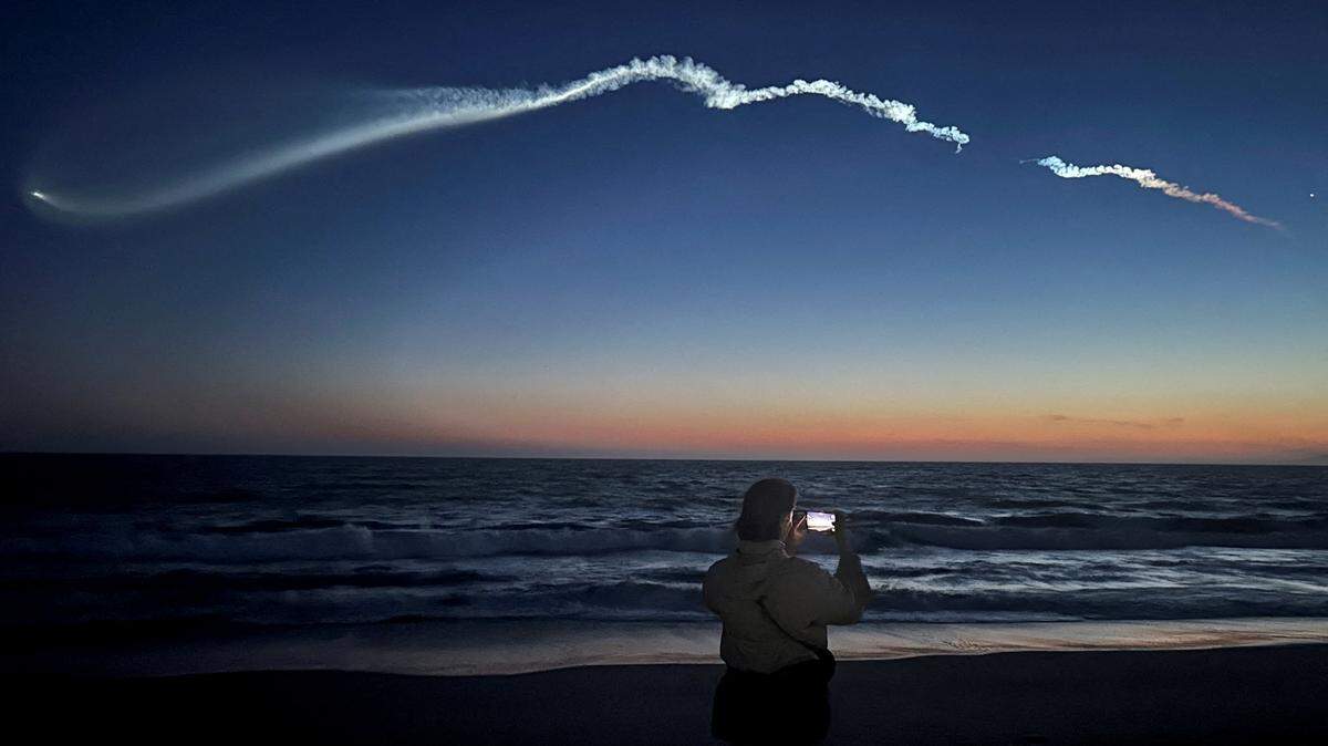 Una persona toma fotografías de la estela que deja el cohete Falcon 9, que transporta satélites Starlink, al cruzar el cielo en el último lanzamiento de SpaceX, visto desde Venice Beach en Los Ángeles, California, el 6 de abril de 2026.
