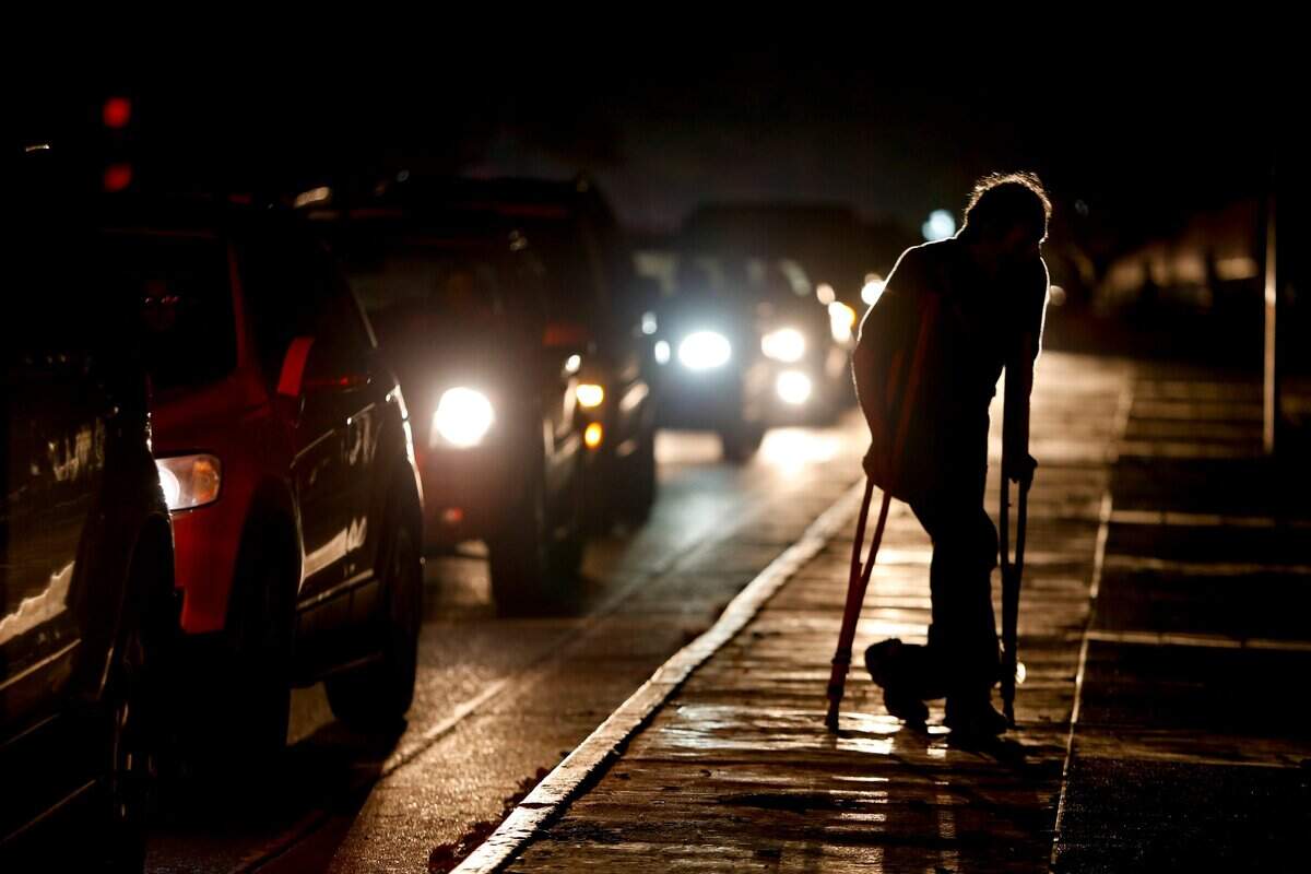 Un hombre con muletas cruza una calle de Caracas en medio de un apagón el 29 de marzo del 2019.