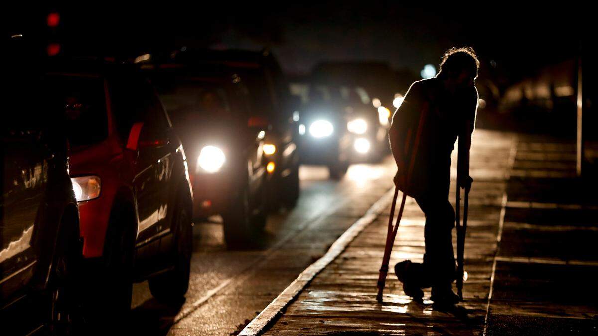 Un hombre con muletas cruza una calle de Caracas en medio de un apagón el 29 de marzo del 2019.