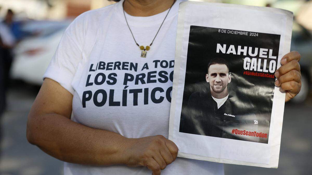 Una mujer muestra un cartel con la imagen del gendarme argentino encarcelado Nahuel Agustín Gallo mientras familiares de presos políticos esperan noticias afuera de la prisión El Rodeo I, en Guatire, estado Miranda, Venezuela, el 25 de febrero de 2026.