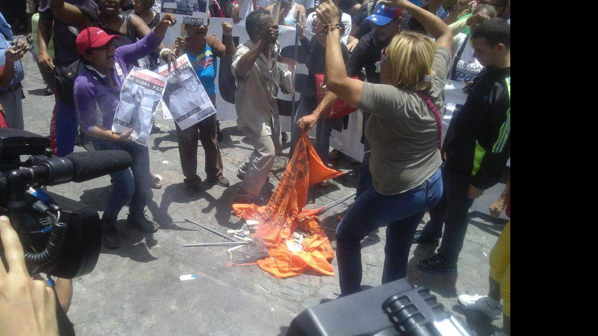 Una foto tuiteada por la Mesa de la Unidad Democrática muestra el momento en que simpatizantes del gobierno de Nicolás Maduro queman banderas del partido Voluntad Popular.  La agresión fue denunciada por seguidores del opositor Leopoldo López que se reunieron en el palacio de Justicia, a la espera de la sentencia contra el líder político, el jueves 10 de septiembre en Caracas. 