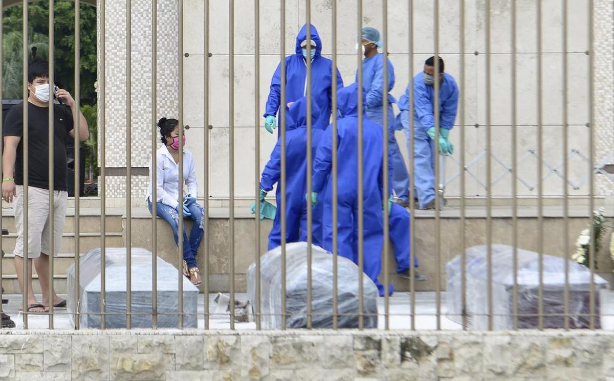 Familiares y empleados de u cementerio esperan para enterrar a presuntas víctimas del coronavirus en Guayaquil, Ecuador, el 1 de abril de 2020. Los ataúdes están forrados de plástico como precaución adicional contra el contagio.