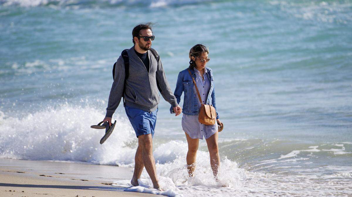 Dos personas caminan tomadas de la mano bajo el clima frío en Miami Beach, Florida, el domingo 13 de marzo de 2022.