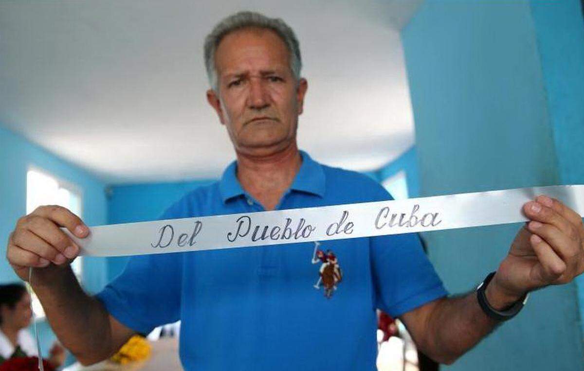 Fotografía fechada el 23 de mayo de 2018 que muestra al informático Carlos Parra mientras exhibe la cinta de una corona de flores escrita manualmente por él, durante una entrevista con Efe en la provincia de Holguín (Cuba).