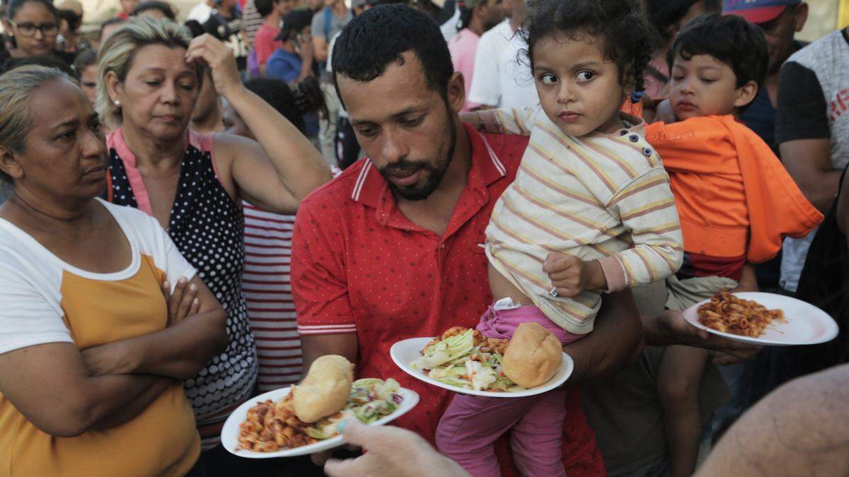 Un padre emigrante y su hija reciben comida en un campamento ubicado en Matamoros, México, a la entrada del Puente Internacional Gateway que conecta la ciudad de Matamoros con Brownsville, en Texas. La iglesia y organizaciones voluntarias en Brownsville llevan agua y alimentos para los migrantes en el lado mexicano de la frontera mientras esperan que se procesen sus solicitudes de asilo.