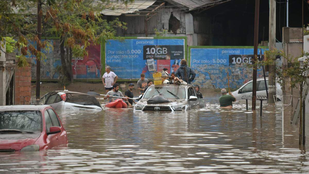 Un grupo de personas en balsas y en una camioneta tratan de mantenerse a flote en una calle inundada de Bahía Blanca, una ciudad a 600 kilómetros al sur de Buenos Aires, Argentina, el viernes 7 de marzo de 2025.