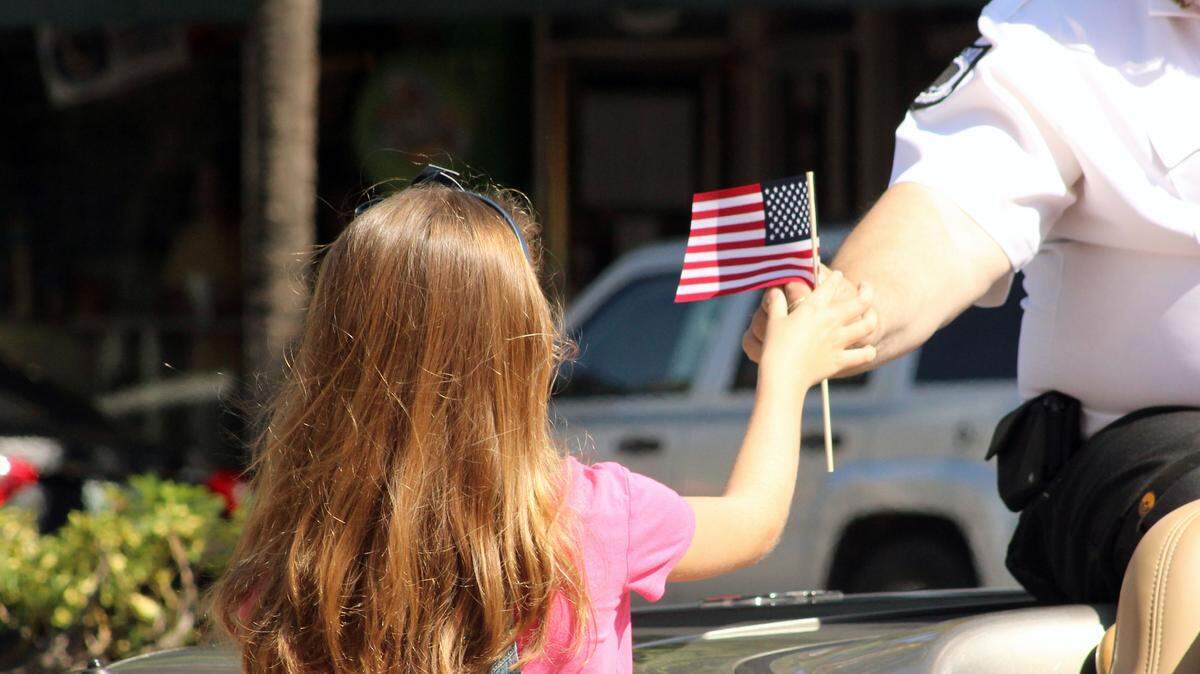 Una niña recibe una bandera americana de la mano de un veterano durante el desfile en Miami Beach, el 11 de noviembre de 2015.
