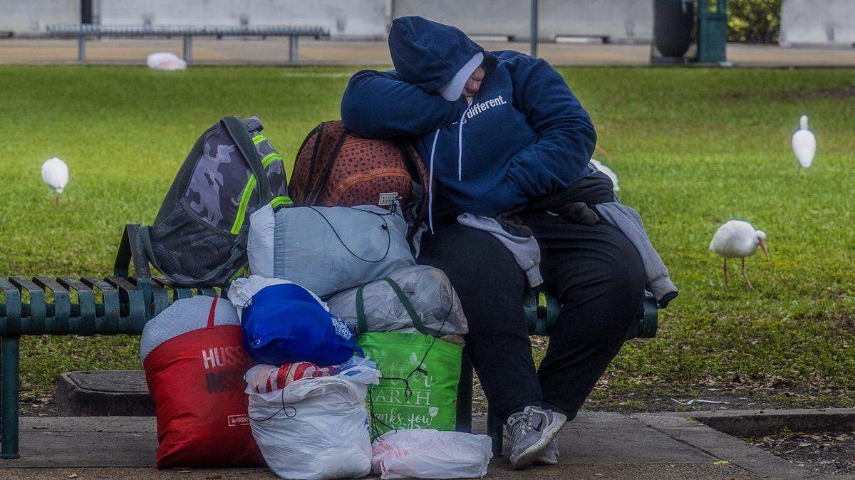 Una mujer desamparada descansa en un banco cerca del Centro de Gobierno en downtown Miami, el sábado 31 de enero de 2026. Voluntarios de Florida Power and Light (FPL) donaron cobijas y ropa de invierno para las personas desamparadas, durante una ola de frío en Miami.