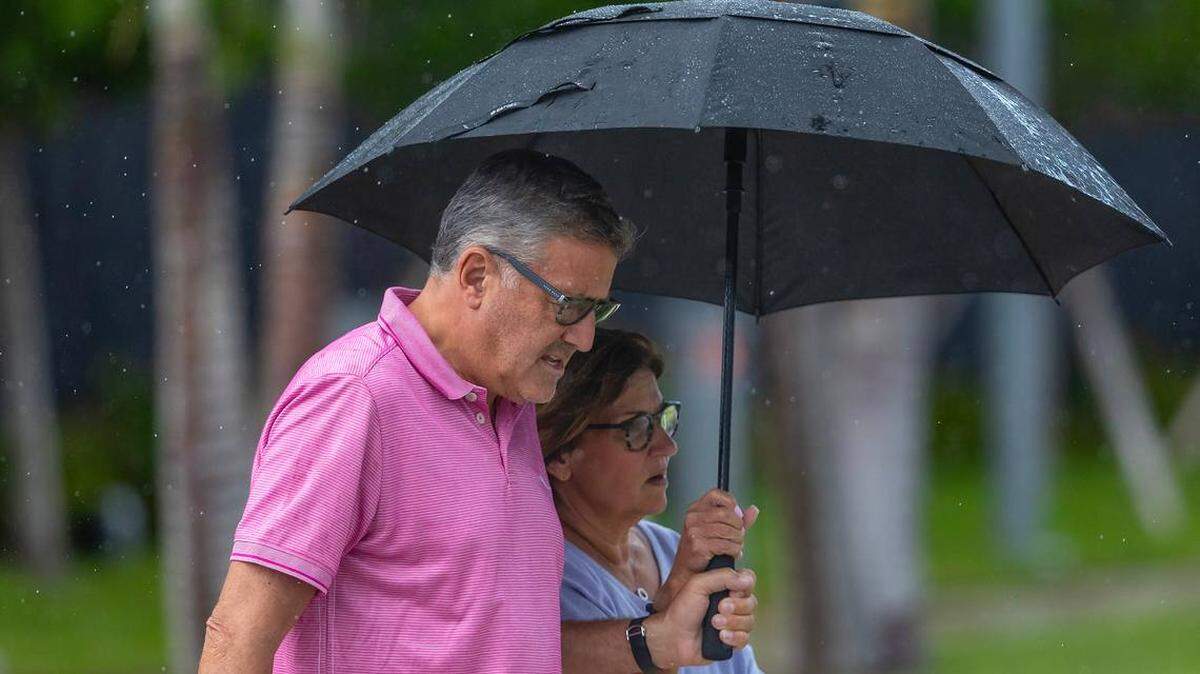 Dos personas se resguardan de la lluvia bajo un paraguas mientras caminan por 18555 Collins Ave en Sunny Isles Beach, Florida, el martes 28 de mayo de 2024. DAVID SANTIAGO dsantiago@miamiherald.com