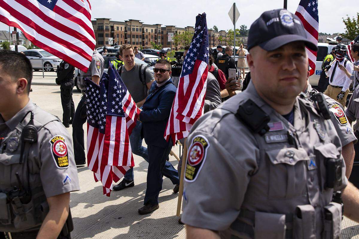 Jason Kessler, al centro vestido de azul, lleva una bandera de EEUU mientras marcha con otros supremacistas blancos en la manifestación del 12 de agosto en Lafayette Square en Washington.