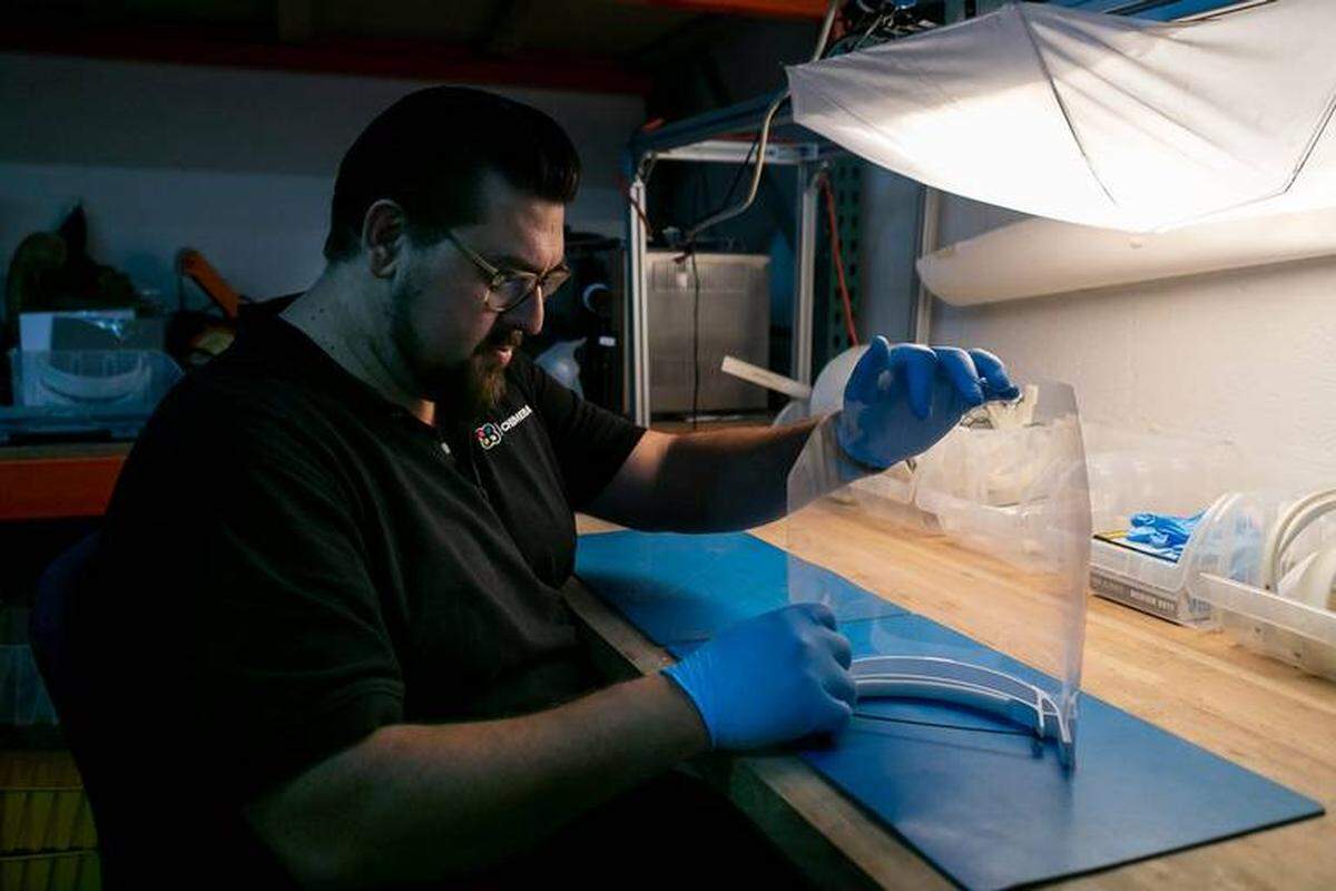 Alexander Hussain, de 37 años, cofundador de 3D Chimera, arma un protector facial con componentes que imprimió en 3D en su oficina en Miami el 1 de marzo de 2020.