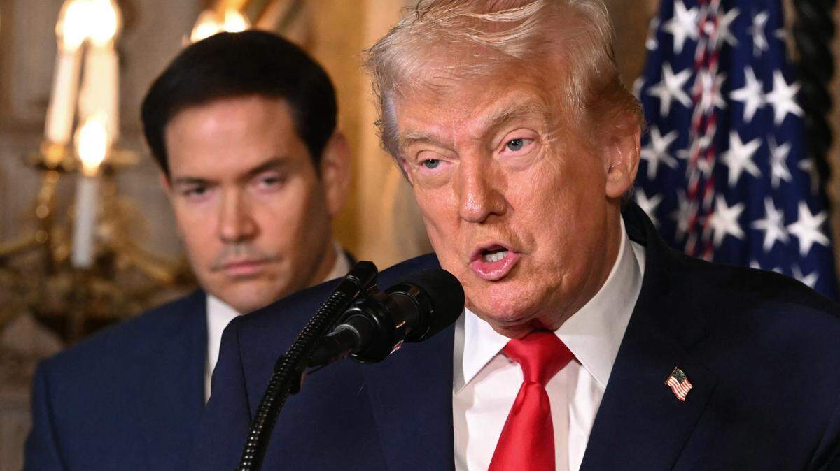 US Secretary of State Marco Rubio looks on as US President Donald Trump speaks after announcing the US Navy's new Golden Fleet initiative, unveiling a new class of warships, at Mar-a-Lago in Palm Beach, Florida, on December 22, 2025. President Donald Trump on December 22 announced a new class of heavily armed warships that will be named after himself -- an honor usually reserved for US leaders who have left office. Two of the Trump-class ships will be built initially but that number could grow substantially in the future, according to the president, who said they will be "some of the most lethal surface warfare ships" and "the largest battleship in the history of our country." Trump made the announcement at his Mar-a-Lago residence in Florida alongside Pentagon chief Pete Hegseth, Secretary of State Marco Rubio and Navy Secretary John Phelan, with images of the planned high-tech vessels on stands nearby. (Photo by ANDREW CABALLERO-REYNOLDS / AFP via Getty Images)