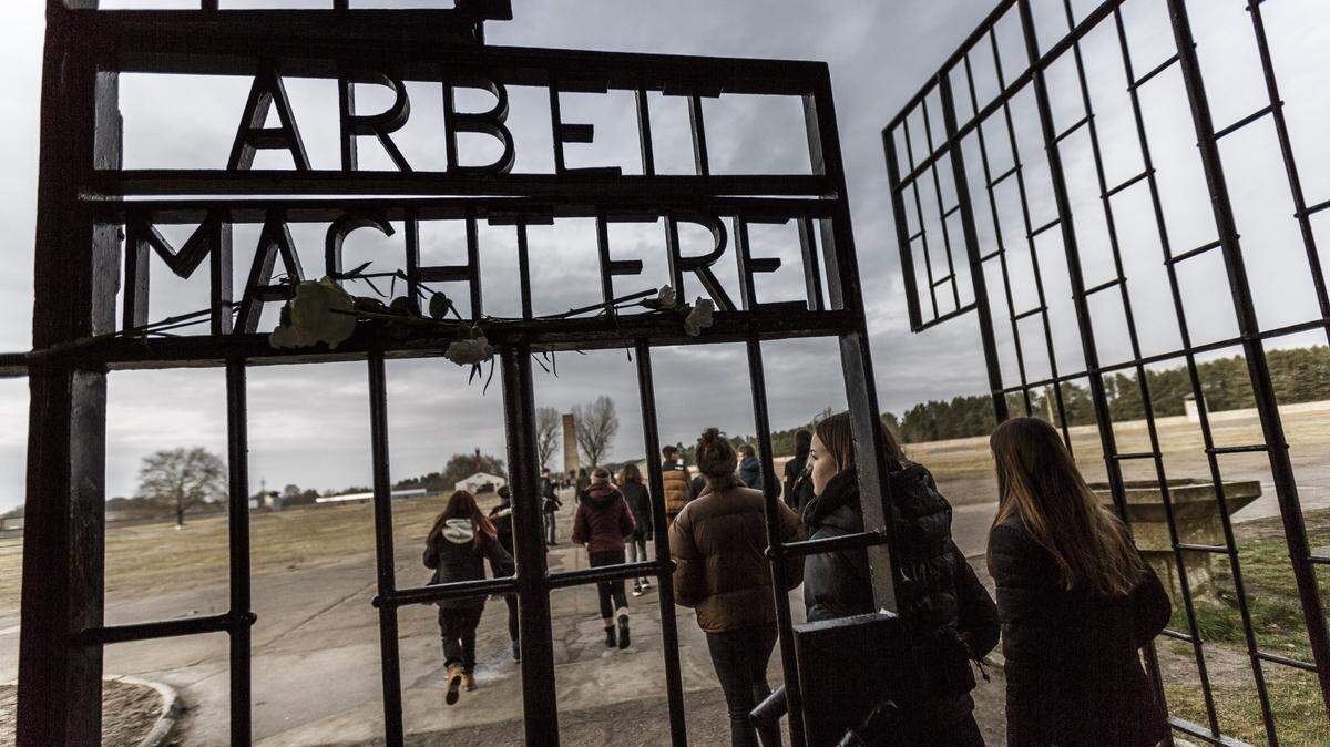 Visitantes caminan por la puerta que tiene la infame frase “Arbeit macht frei” (El trabajo te liberará), en el memorial Sachsenhausen en honor a las víctimas del campo de concentración Auschwitz, en Oranienburg, Alemania, el lunes 27 de enero de 2020. 