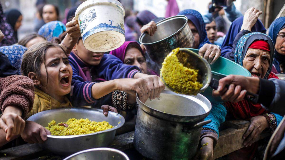 Decenas de palestinos, entre ellos niños, reciben comida en un centro de distribución en Ciudad de Gaza, el viernes 27 de diciembre de 2024.