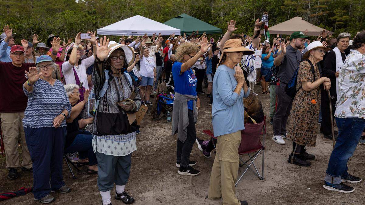 An interfaith coalition hold their hands up in prayer outside Alligator Alcatraz on Sunday, August 17, 2025, in Ochopee, Fla.
