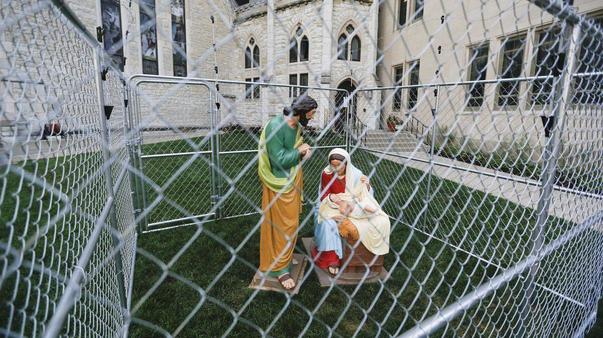 Foto del martes 3 de julio de 2018 muestra estatuas de María, José y el niño Jesús en una jaula con alambres de púas en el césped de la Christ Church Cathedral de Monument Circle en Indianápolis.