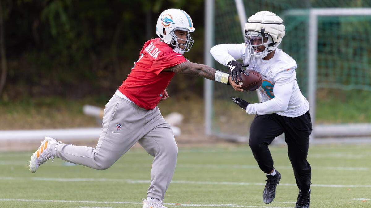 El quarterback de los Dolphins de Miami Tua Tagovailoa le pasa el ovoide al running back Salvon Ahmed en una práctica del equipo el 1ro de noviembre de 2023 en Frankfurt, Alemania.