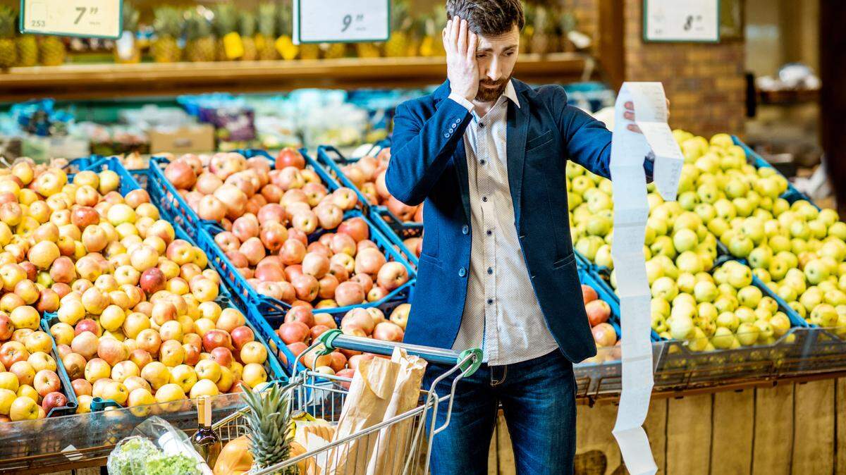 Retrato de un hombre elegante con emociones conmocionadas con una lista de compras muy larga mientras compra comida en el supermercado