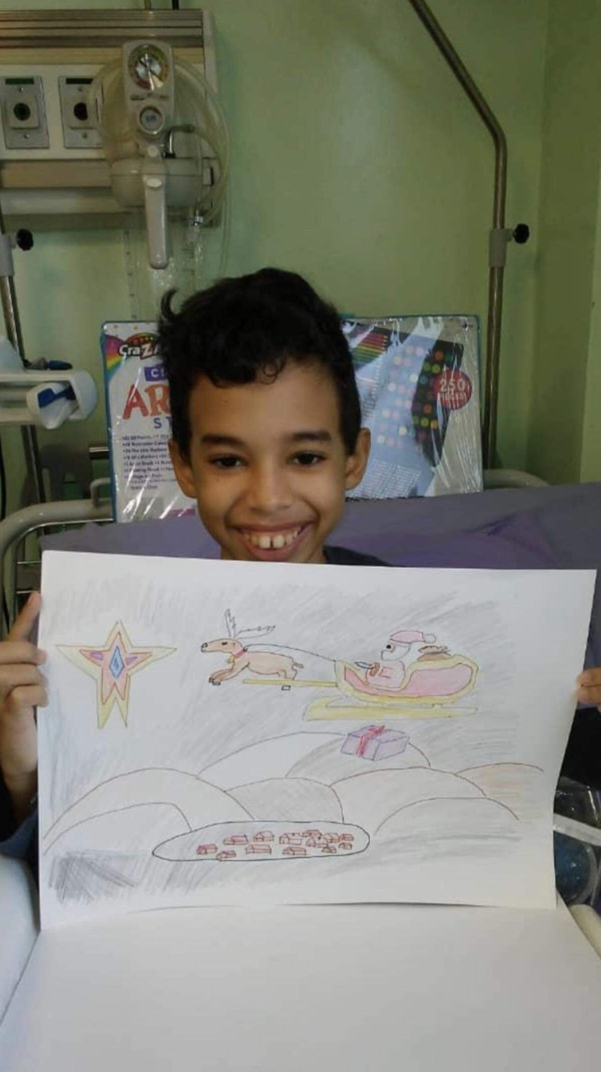 José Camilo posa junto a un dibujo de Navidad. Según la madre del niño, su habitación en el Instituto de Hematología e Inmunología se asemejaba a una galería de arte porque tenía las paredes llenas de sus creaciones.