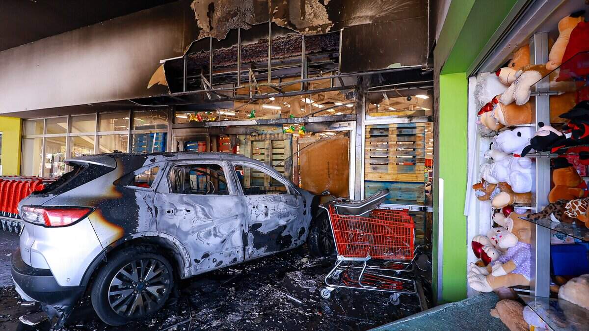 Un automóvil incendiado bloquea la entrada de una tienda en un centro comercial el 22 de febrero de 2026 en Guadalajara, México.