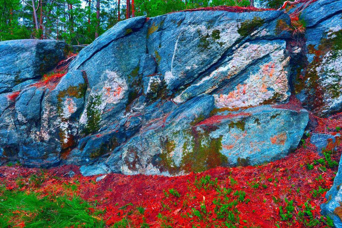 Una foto con colores muestra varias pinturas en color rojo en la roca.