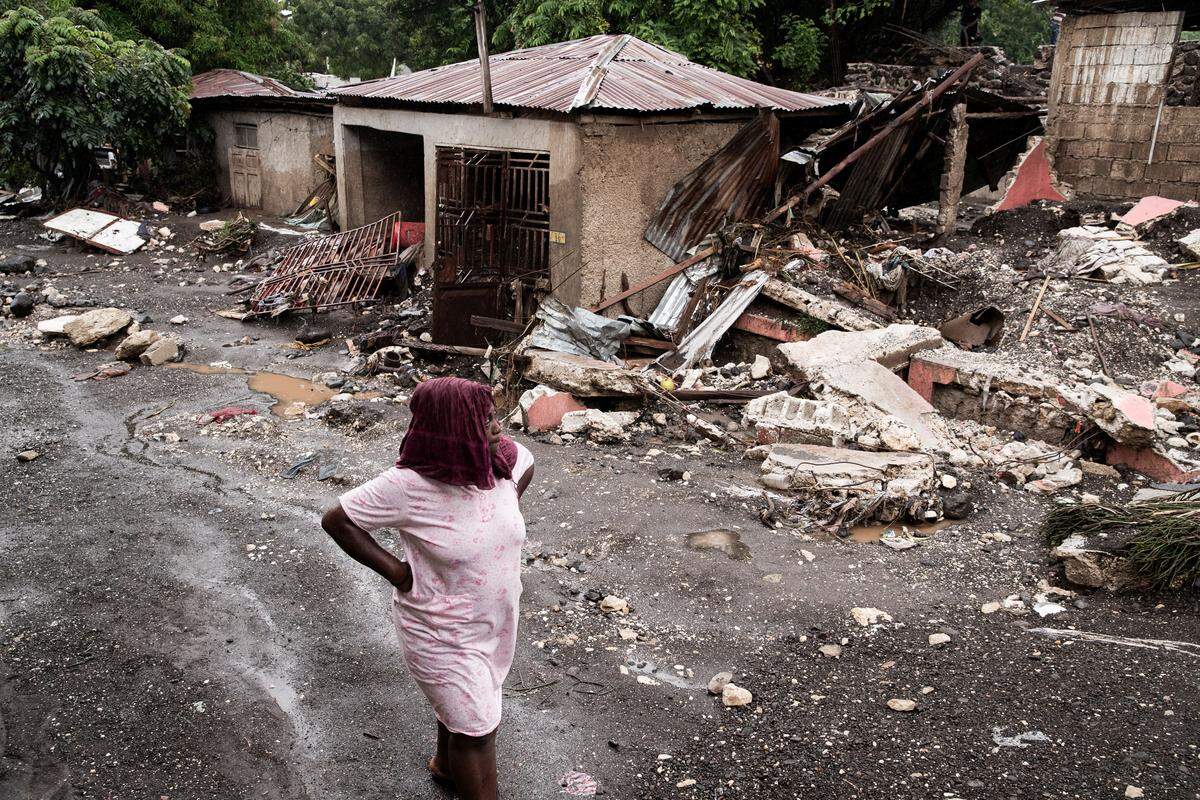 TOPSHOT - A woman walks past her house that was destroyed by Hurricane Melissa in Petit-Goave, 68km southwest of Port-au-Prince, on October 30, 2025. Hurricane Melissa was moving towards Bermuda on Thursday after ripping a path of destruction through the Caribbean that left at least 20 people dead in Haiti, and parts of Jamaica and Cuba in ruins. (Photo by Clarens SIFFROY / AFP) (Photo by CLARENS SIFFROY/AFP via Getty Images)