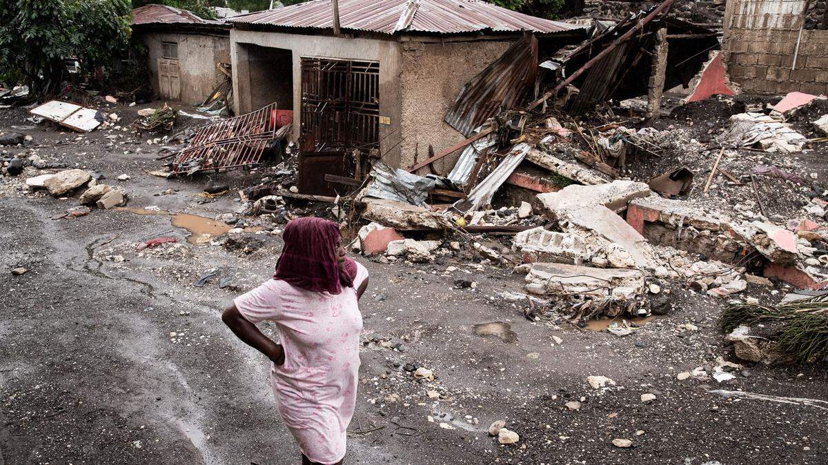 TOPSHOT - A woman walks past her house that was destroyed by Hurricane Melissa in Petit-Goave, 68km southwest of Port-au-Prince, on October 30, 2025. Hurricane Melissa was moving towards Bermuda on Thursday after ripping a path of destruction through the Caribbean that left at least 20 people dead in Haiti, and parts of Jamaica and Cuba in ruins. (Photo by Clarens SIFFROY / AFP) (Photo by CLARENS SIFFROY/AFP via Getty Images)
