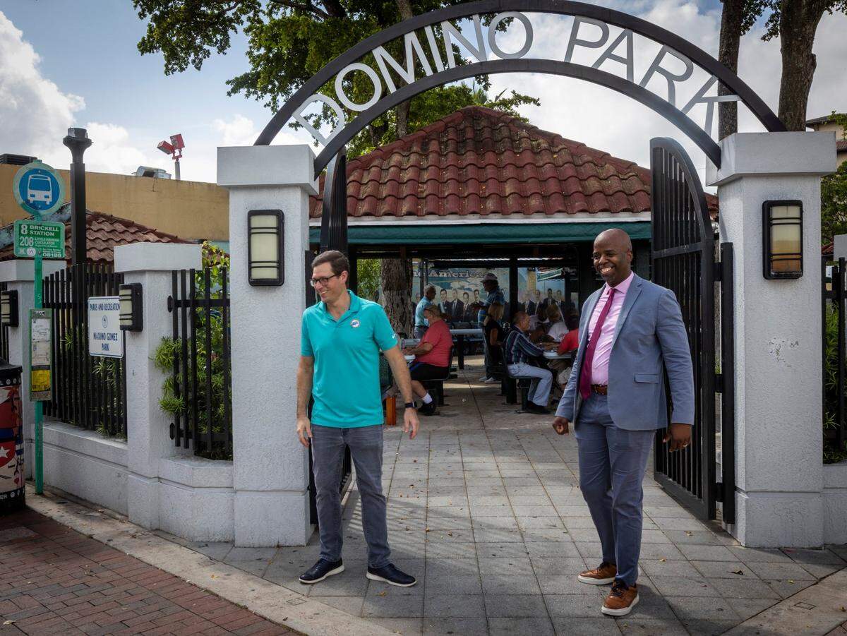 Marcus Bach Armas, director de asuntos legales de los Dolphins (izq.) y Jason Jenkins Sr, Vicepresidente de Asuntos de Comunicación y de la Comunidad del equipo posan en el parque Máximo Gómez, también conocido como Parque del Dominó, durante un recorrido por La Pequeña Habana en Miami, el 21 de julio de 2021.