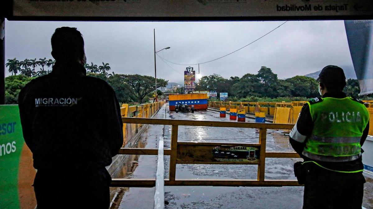 Los oficiales de migración colombianos son vistos usando máscaras faciales protectoras para evitar la propagación del nuevo Coronavirus, COVID-19, mientras se encuentran en el Puente Internacional Simón Bolívar, en la frontera con Venezuela, en Cúcuta, Colombia, el 14 de marzo de 2020.
