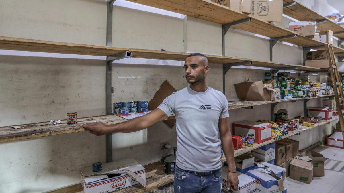 Un empleado muestra los estantes casi vacío de un supermercado en Rafah, Franja de Gaza, en la frontera con Egipto, el domingo 5 de noviembre de 2023.