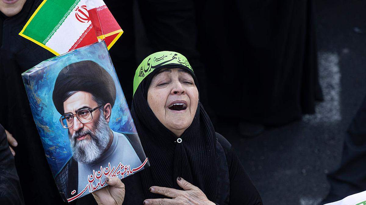 Una mujer se lamenta y sostiene un cartel mientras miles de personas se reúnen en la Plaza Enghelab para una manifestación a favor del gobierno después de que los medios estatales iraníes confirmaran la muerte del ayatolá Ali Khamenei, el domingo 1 de marzo de 2026 en Teherán, Irán.