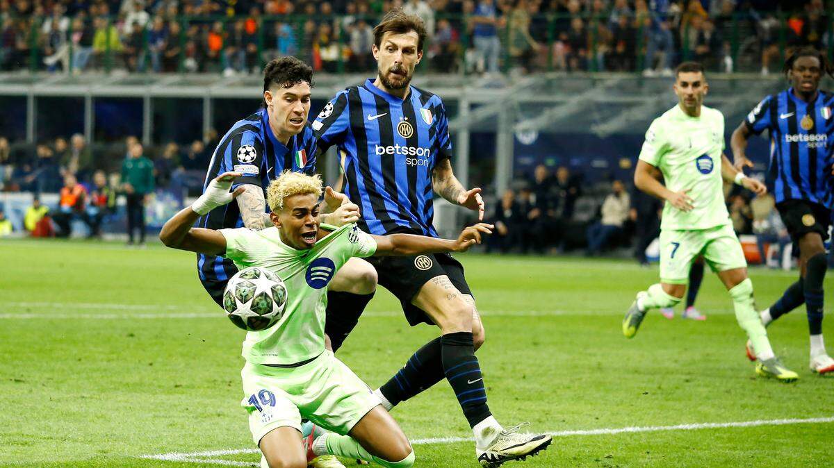 El jugador de Barcelona Lamine Yamal (izq.) es marcado por Alessandro Bastoni y Francesco Acerbi (der.), del Inter, en el partido de vuelta de la semifinal de la Liga de Campeones, celebrado el 6 de mayo de 2025 en Milán.