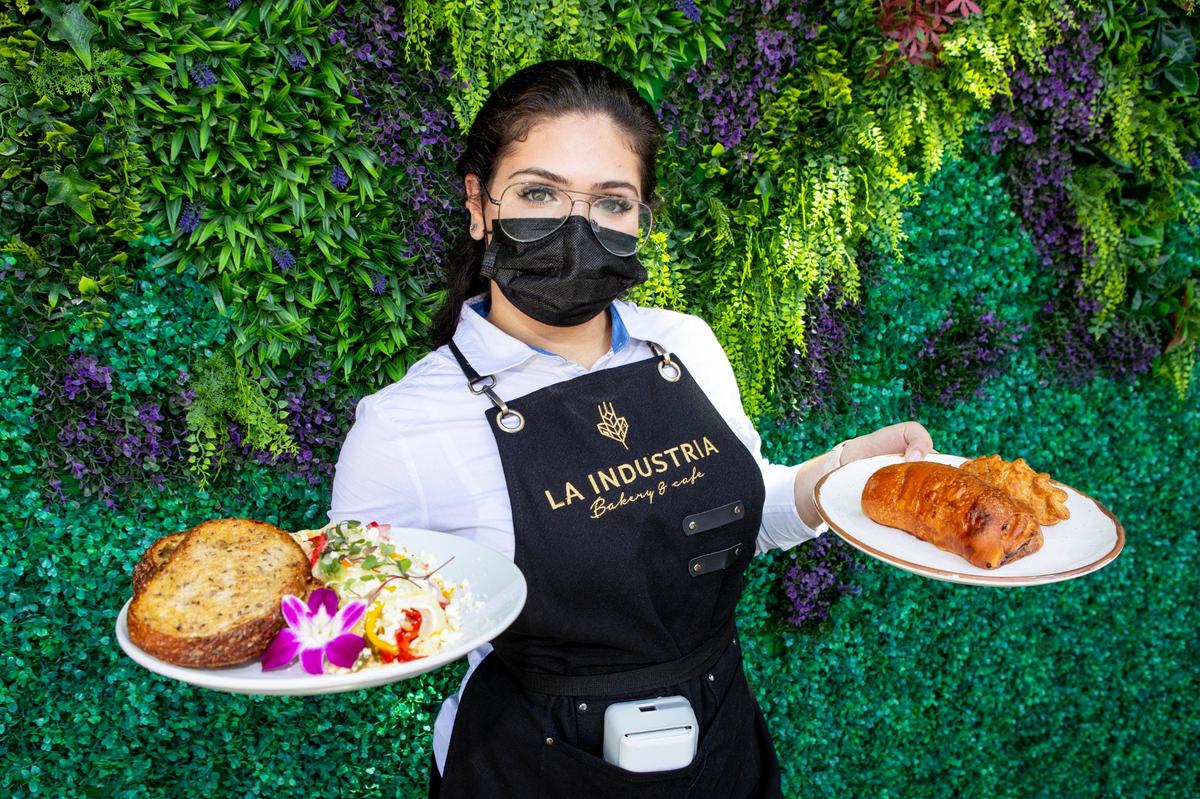 An employee from La Industria Bakery and Cafe showcases some dishes for the grand-opening of the bakery inside Bayside Marketplace in Downtown-Miami, Florida, on Friday, April 9, 2021.