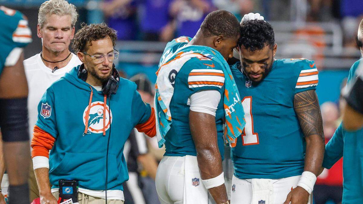 El tight end de los Dolphins Jonnu Smith (centro) habla con Tua Tagovailoa (1) después de que el quarterback se lesionó al tratar de ganar unas yardas y chocar con el safety de Buffalo Bills Damar Hamlin, en el partido celebrado el  12 de septiembre en el Hard Rock Stadium de Miami Gardens. 