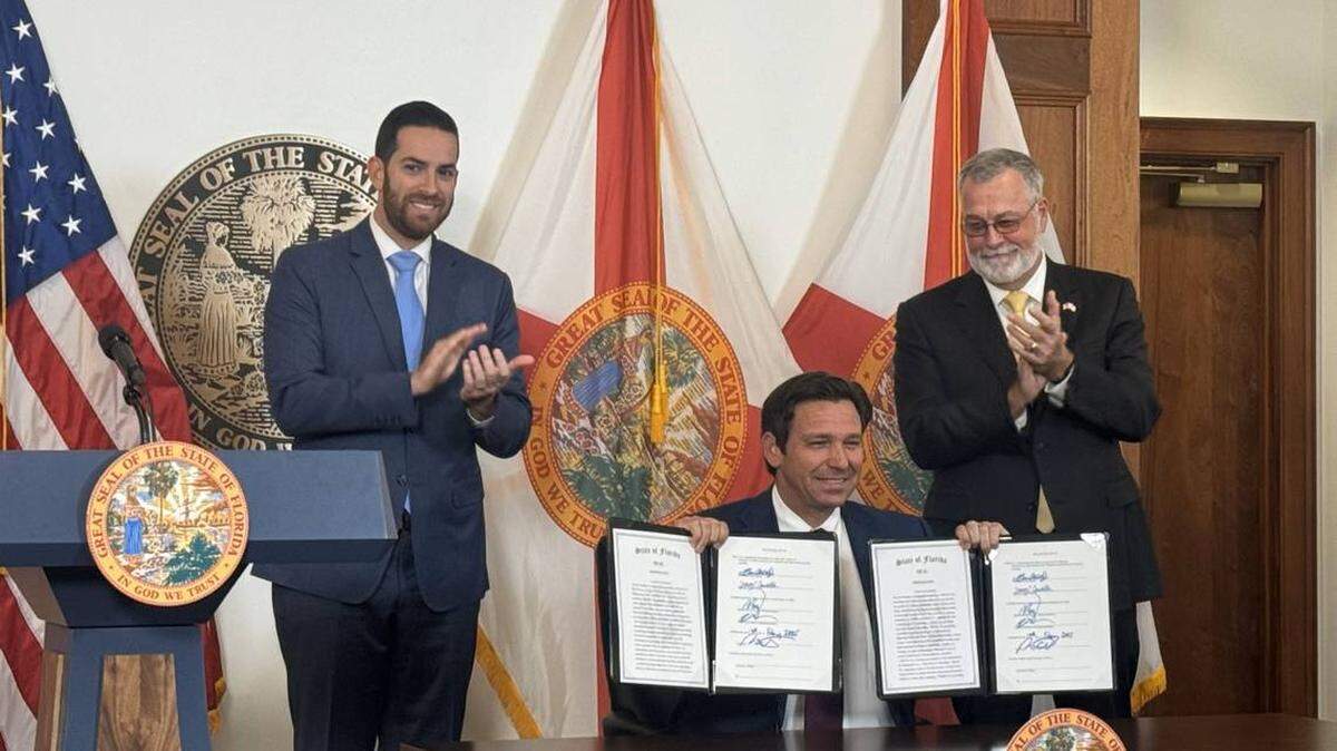 El gobernador de la Florida, Ron DeSantis, en la foto entre el presidente de la Cámara de Representantes, Daniel Pérez (izquierda), y el presidente del Senado, Ben Albritton (derecha), cuando firmaba el 13 de febrero de 2025 dos proyectos de ley aprobados en una sesión especial de la Legislatura de Florida.