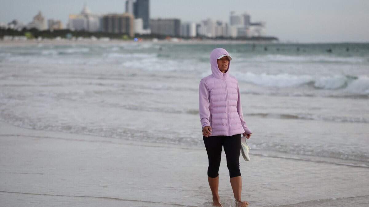 MIAMI BEACH, FLORIDA - NOVEMBER 11: Martina Filitova wears a jacket to keep warm in the chilly air as she walks along the beach on November 11, 2025 in Miami Beach, Florida. A cool blast of air moved through the area in the morning with temperatures in the upper-40s all across South Florida, and with wind chill it was in the low- to mid-40s. (Photo by Joe Raedle/Getty Images)