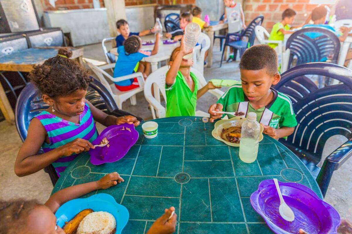 Estelita Gómez, de 7 años, y Alexis Torres, de 8, junto a otros niños, comen con la ayuda de la ONG Pasión Petare, en Petare, Venezuela. A menudo es la única comida que los niños reciben los días de práctica.