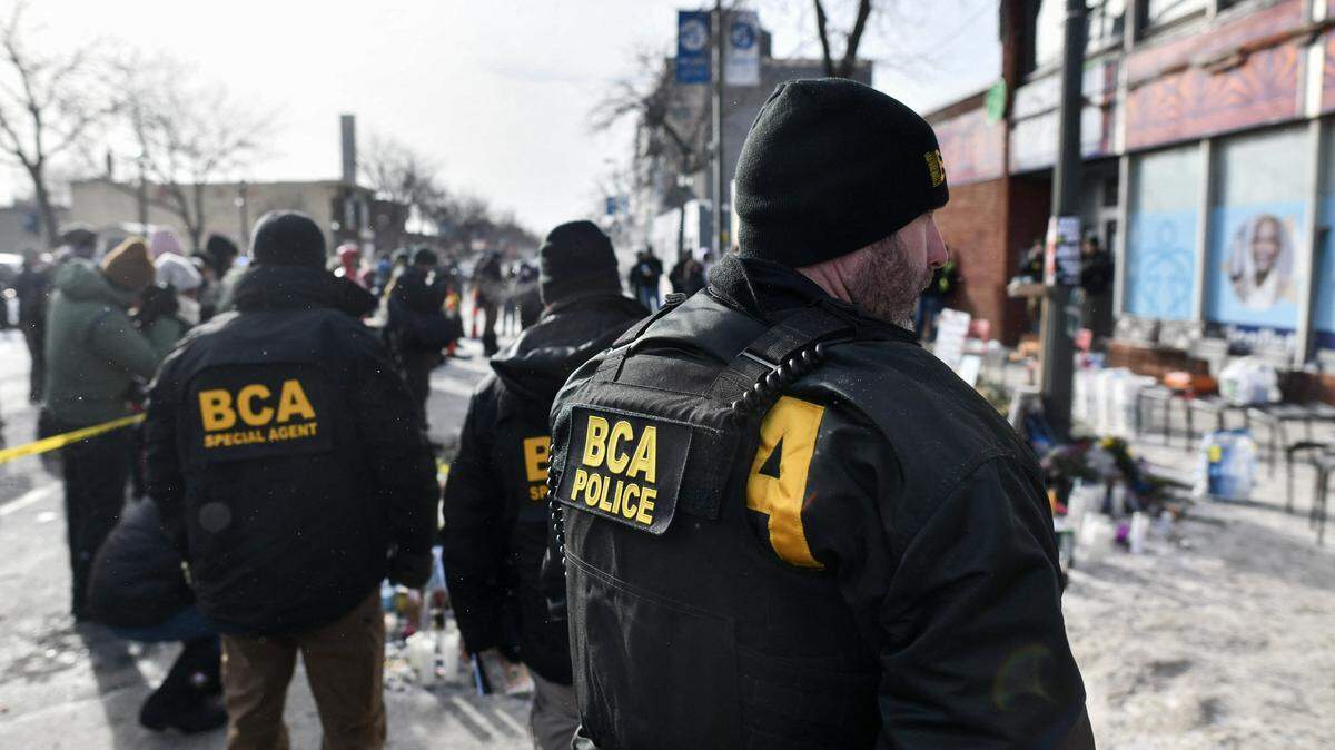 Bureau of Criminal Apprehension police officers survey the scene near a makeshift memorial in the area where Alex Pretti was shot dead a day earlier by federal immigration agents in Minneapolis, Minnesota, on January 25, 2026. On January 24, federal agents shot dead US citizen Alex Pretti, a 37-year-old ICU nurse, while scuffling with him on an icy roadway, less than three weeks after an immigration officer shot and killed Renee Good, also 37, in her car. His killing sparked new protests and impassioned demands by local leaders for the Trump administration to end its operation in the city. (Photo by Octavio JONES / AFP via Getty Images)