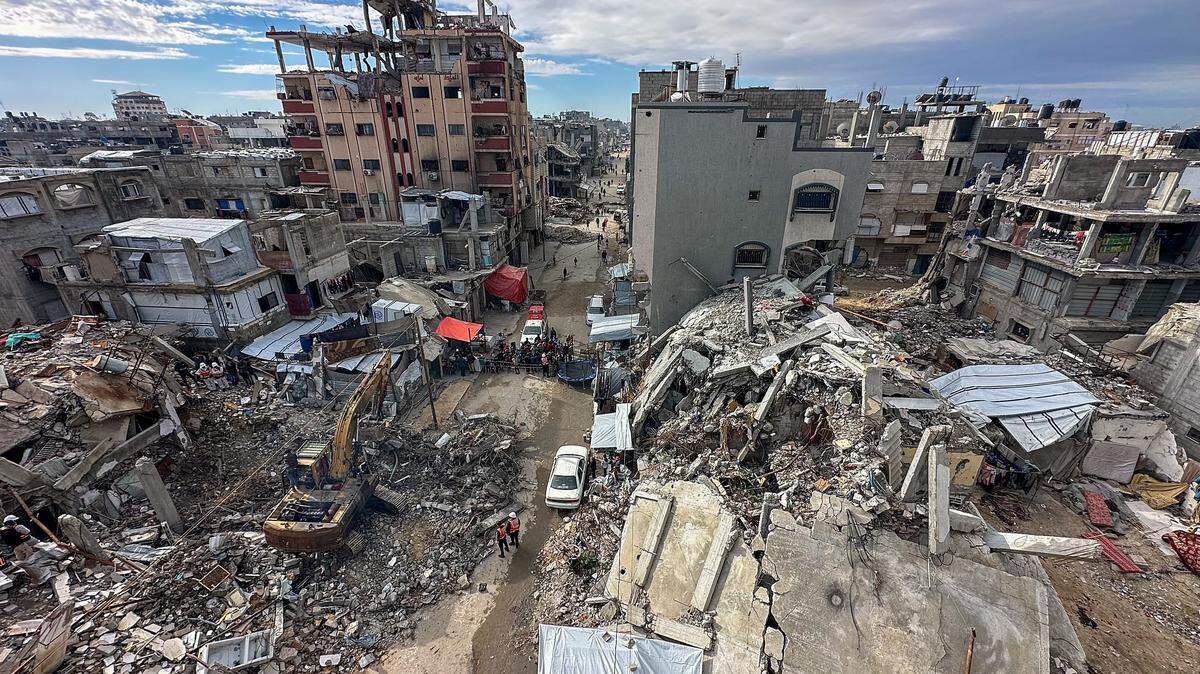 An excavator removes debris as people watch during a search operation in the Al-Amal neighborhood of Khan Yunis, Gaza Strip, on December 20, 2025. Civil defense teams are conducting search operations for the bodies of the Abu Hilal family in the Al-Amal neighborhood, months after they were killed on August 13, 2025. Search efforts have been hindered by a severe shortage of heavy equipment and access restrictions in the area. (Photo by Doaa Albaz / Middle East Images / AFP via Getty Images)
